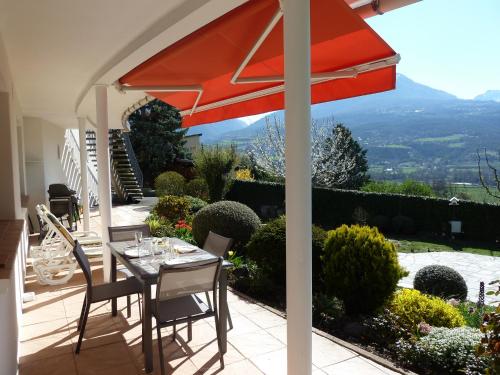 a table with a red umbrella on a patio at Vue sur les montagnes in Embrun