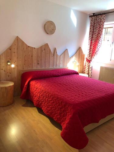 a bedroom with a red bed with a wooden headboard at Appartamenti Viviani in Pinzolo