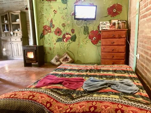 1 dormitorio con 1 cama y papel pintado con motivos florales en Pintoresca Cabaña Céntrica a pasos del río en Mina Clavero