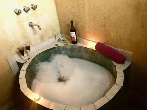 a bath tub filled with snow and a bottle of wine at Pintoresca Cabaña Céntrica a pasos del río Mina Clavero in Mina Clavero