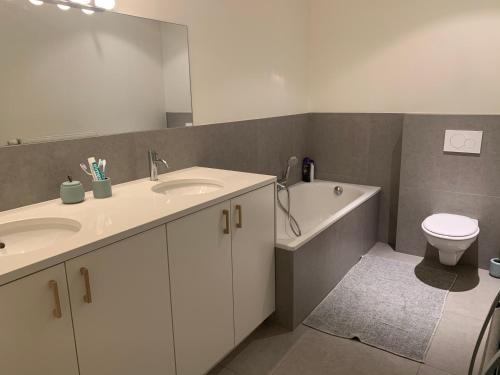 a bathroom with two sinks and a toilet and a mirror at Appartement Delmare in De Panne