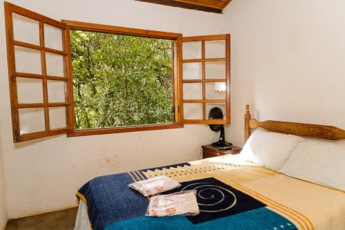a bedroom with a bed and a window at Chalés do Beto em Macacos in Macacos
