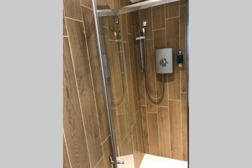 a shower in a bathroom with a wooden wall at Alison15 - Superior Clifton Studio Apartment in Bristol