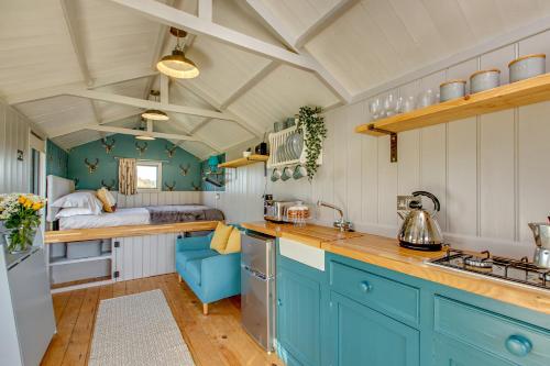 a kitchen with blue cabinets and a bed in the background at Stag in Felbrigg