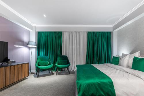 une chambre d'hôtel avec un lit vert et deux chaises vertes dans l'établissement Hotel Kristal Focsani, à Focşani