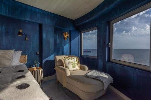 a bedroom with blue walls and a chair and windows at Okulus Madeira in Funchal