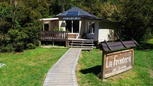 a small house with a sign in the grass at La Frontera Bed & Breakfast, Valle Cochamó in Cochamó