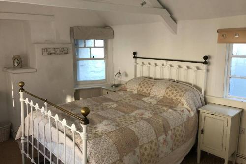 a bedroom with a bed and two windows at Molls Yard Traditional Cottage in Port Isaac