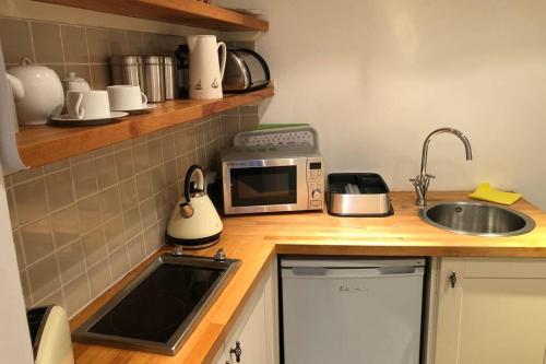 a small kitchen with a sink and a microwave at Molls Yard Traditional Cottage in Port Isaac