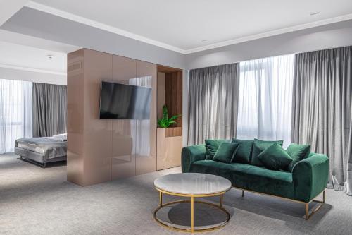 a living room with a green couch and a table at Hotel Kristal Focsani in Focşani