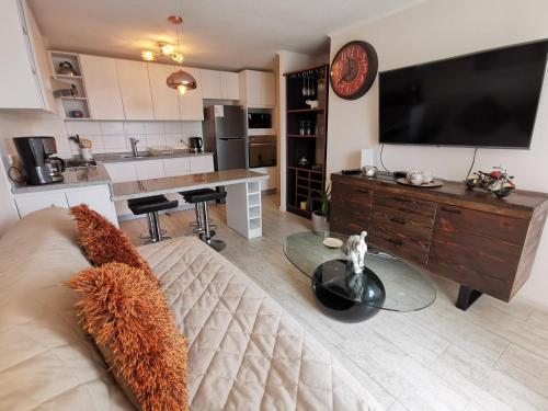 a living room with a couch and a large television at Departamento en Avenida Del Mar in La Serena