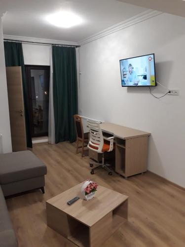 een woonkamer met een bureau en een tv aan de muur bij Aparthotel Sweet Home Acasa in Constanţa