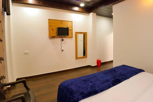 a bedroom with a bed and a tv on the wall at Grand Kailash Khajjiar in Dalhousie