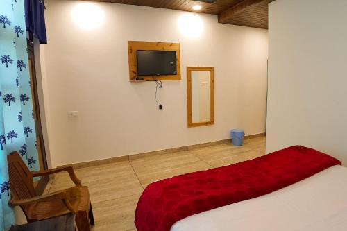 a bedroom with a bed and a tv on a wall at Grand Kailash Khajjiar in Dalhousie