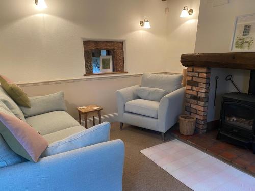 a living room with a couch and a chair and a fireplace at Rock View Cottage, 2 bedrooms near Alton Towers in Alton