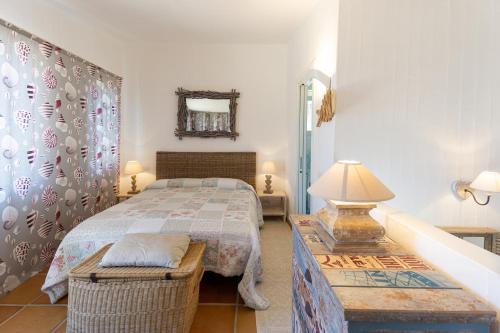 a bedroom with a bed and a table with a lamp at BGItalianVacation - Ville Li Conchi in Castiadas