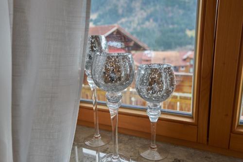 three wine glasses sitting in front of a window at Ferienwohnungen Kappeler in Bad Hindelang