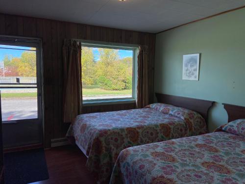a hotel room with two beds and a window at Motel Des Erables in Coteau-du-Lac