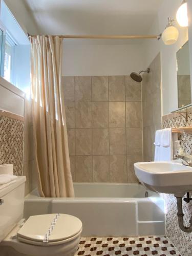 a bathroom with a tub and a toilet and a sink at Motel Des Erables in Coteau-du-Lac