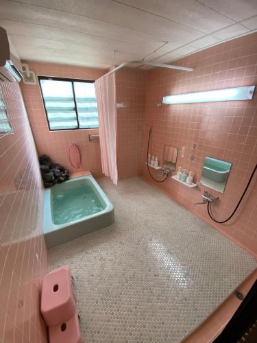 a pink bathroom with a tub and a sink at Nozawa Dream Central in Nozawa Onsen