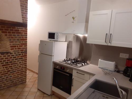 a kitchen with white cabinets and a stove and refrigerator at Gîte de la Ferme de la Côte in Les Damps