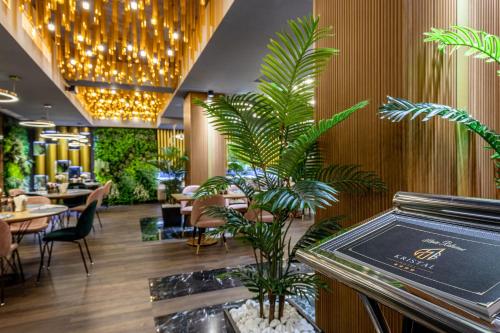 a restaurant with tables and chairs and palm trees at Hotel Kristal Focsani in Focşani