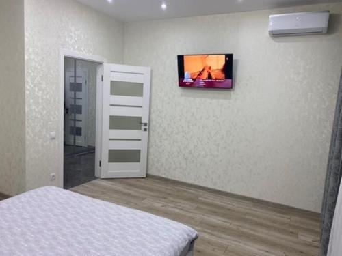 um quarto com uma televisão numa parede com uma cama em Люкс Апартаменты в центре города ,ЖК Театральный em Rivne