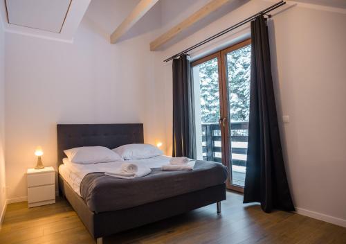 een slaapkamer met een bed en een groot raam bij Aston -domek przy lesie, przestronny in Karpacz