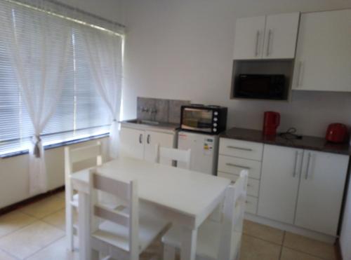 a kitchen with a white table and a microwave at Spacious 1bed + braai 13km to Paternoster beach in Vredenburg