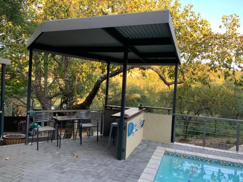 a pavilion with a table and chairs next to a pool at Birds Babble Self Catering in Nelspruit