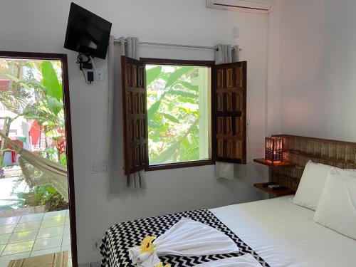 a bedroom with a bed with a television and a window at Pousada do Mineiro in Trancoso