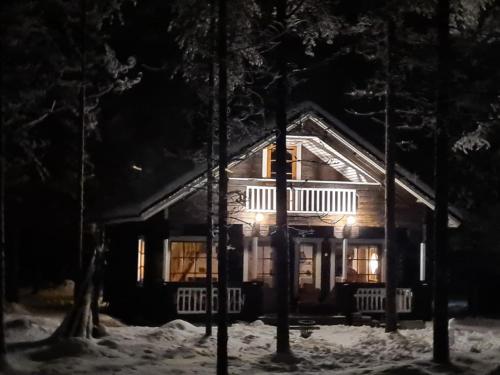 a log cabin in the snow at night at PyhäBerry in Pelkosenniemi