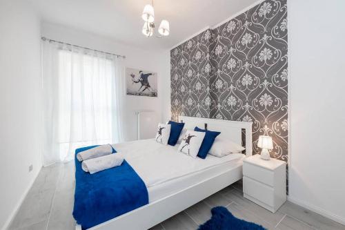 a bedroom with a white bed with blue pillows at Banksy Apartment - Ilumino in Łódź