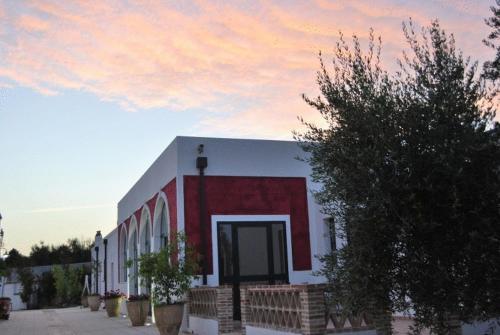 a red and white building with a red and white door at Hotel Giardino Giamperduto in Bernalda