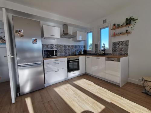 a kitchen with white appliances and a wooden floor at Le Kerdun Bord de mer tout à pied in Le Pouliguen