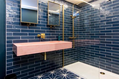 a bathroom with a pink sink and blue tiles at The Brewery Apartments in Stockport