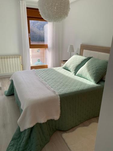 a bedroom with a green bed with a window at Apartamento Rio San Isidro 1 in Felechosa