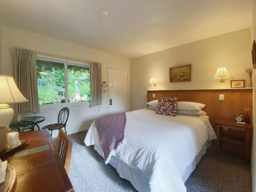 a bedroom with a bed and a desk and a window at Emerald Valley Inn in Port Angeles