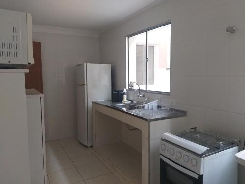 a white kitchen with a sink and a refrigerator at Antonia Haddad in Lorena