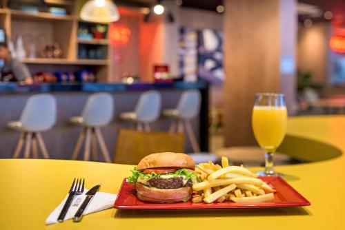 a plate with a hamburger and french fries and a glass of juice at ibis Sao Paulo Tatuape in Sao Paulo