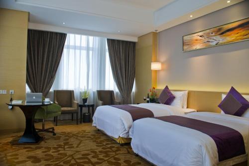a hotel room with two beds and a desk at Yangzhong Firth Jinling Grand Hotel in Yangzhong