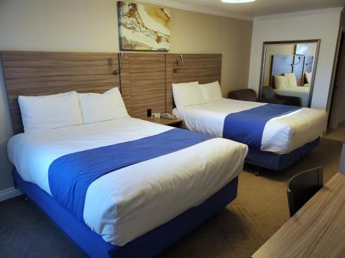 a hotel room with two beds and a mirror at Exchange Club Motel in Beatty