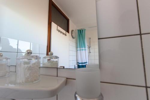 a white bathroom with a sink and a mirror at Blick über Bonn ins Siebengebirge in Bonn