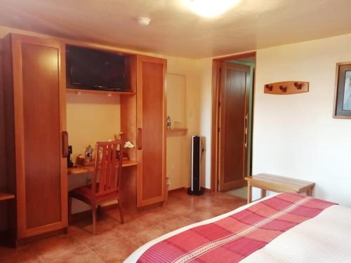 a bedroom with a bed and a desk and a television at Casa Tsaya Hotel Boutique in Bernal