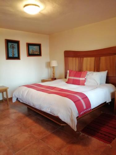 a bedroom with a large bed with a red and white blanket at Casa Tsaya Hotel Boutique in Bernal