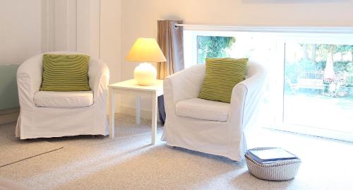 a living room with two chairs and a table with a lamp at Relais de Chasse la Chaignaie in Montaigu-Vendée