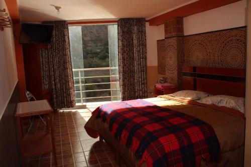 a bedroom with a bed and a large window at Hotel Manantial in Churín