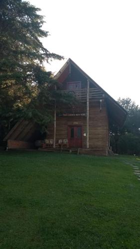 a log cabin with a red door on a green lawn at CHALÉ ESTÂNCIA OURO VERDE in Lages