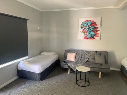 a bedroom with a bed and a couch and a chair at Hello Adelaide Motel and Apartments in Adelaide