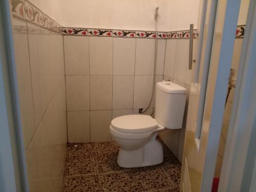 a bathroom with a white toilet in a room at Rumah Ukhi in Yogyakarta